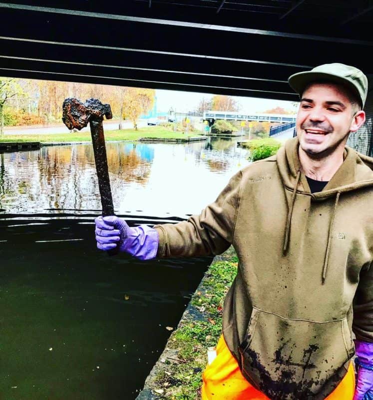 magnet fisher drží sekeru nájdenú v kanály