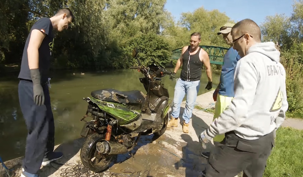 Štyria magnet fisheri okolo motorky, ktorú našli v potoku