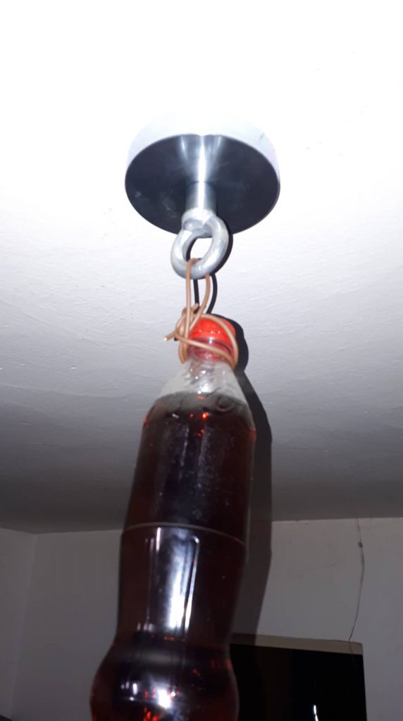 Magnet prichytený na strope udrží fľašu plnú coly